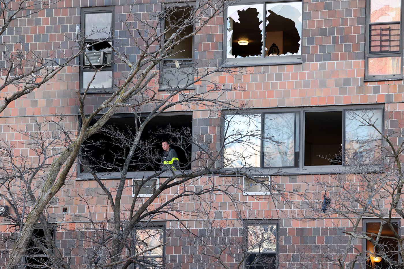 An FDNY firefighter looks out from a burned apartment at the Twin Parks North West building Monday afternoon.